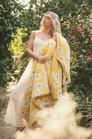 Lush Butter Yellow Floral Blanket draped over a model in a floral garden, showcasing its vibrant yellow hue and floral design.