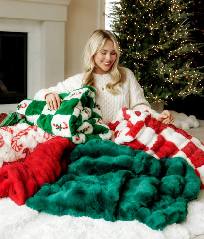 Woman sitting in front of christmas tree with 5 christmas blankets
