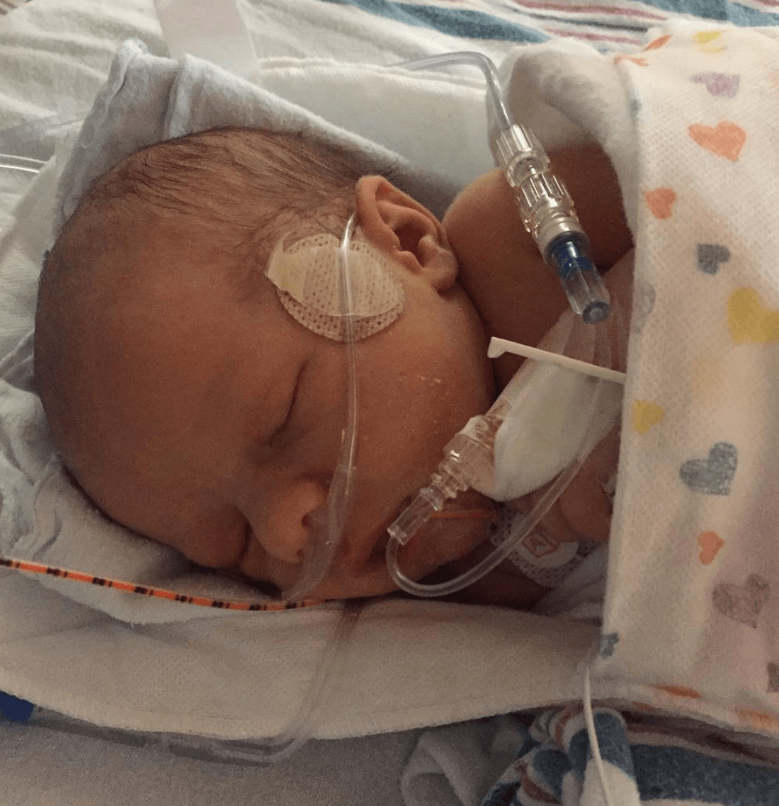 Heart of Minky: Sloan, a newborn baby in a hospital with medical equipment, wrapped in a colorful blanket.