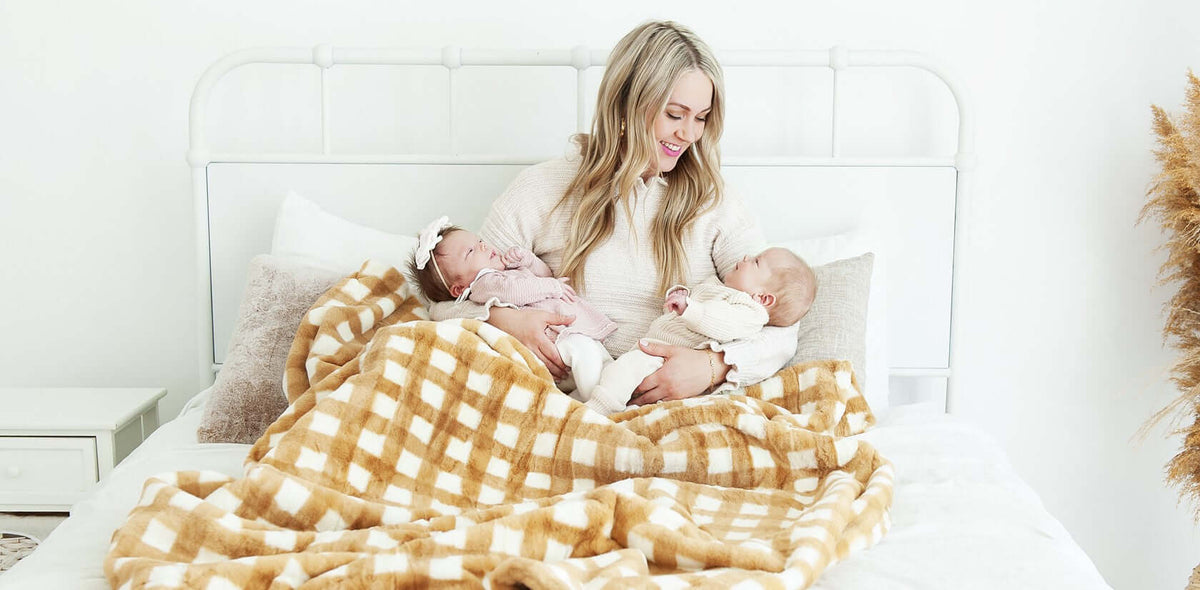 Gentle Ways to Calm Your Baby: Tips for Soothing a Restless Infant - Mother with twin infants in cozy blanket on bed.