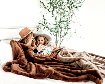 Two kids cozy under blankets reading together, demonstrating 14 Tips to Get Your Kids into Reading.