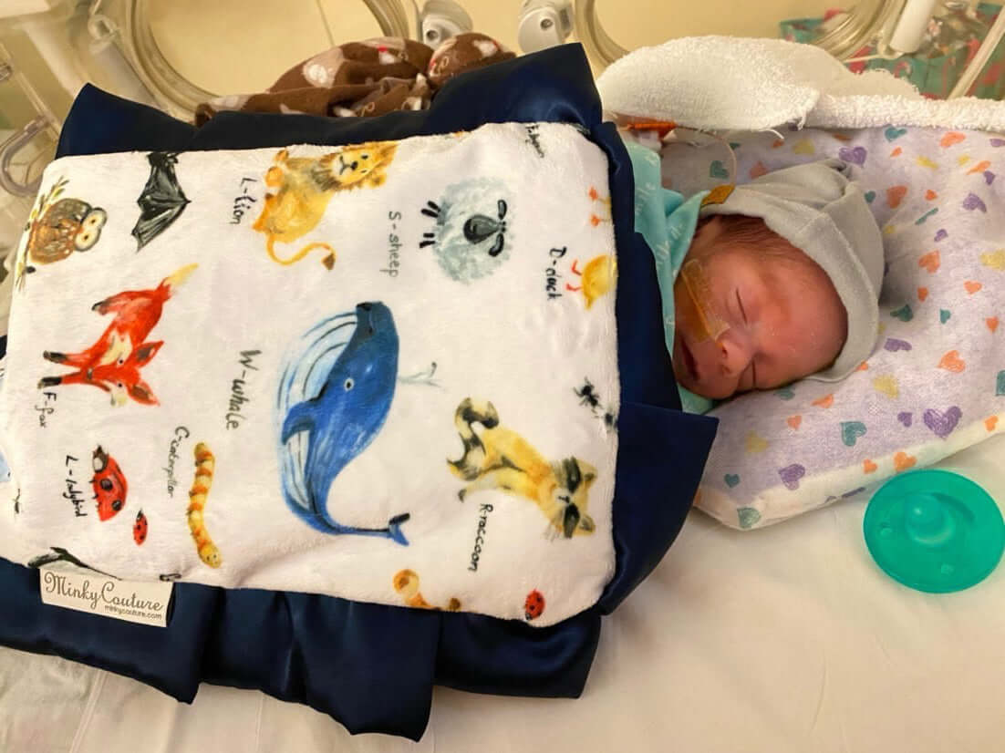 Heart of Minky: Leo - newborn baby swaddled in colorful animal-patterned blanket in NICU.