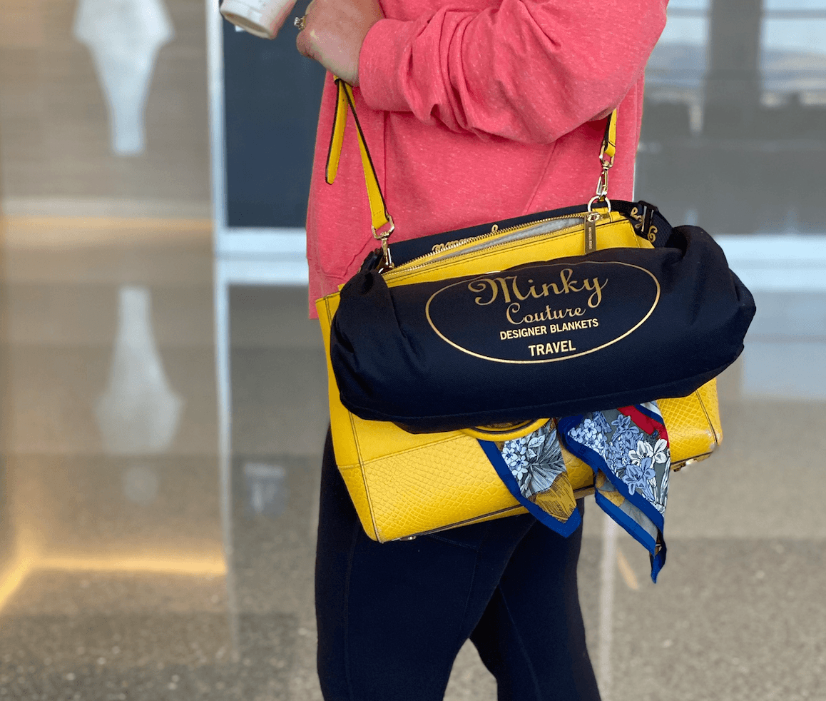 Woman carrying a yellow handbag and black travel blanket bag, suitable for a Back-To-School Teacher Gift Guide.
