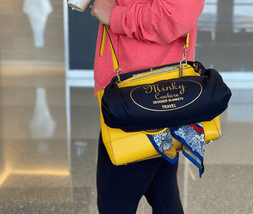 Woman carrying a yellow handbag and black travel blanket bag, suitable for a Back-To-School Teacher Gift Guide.