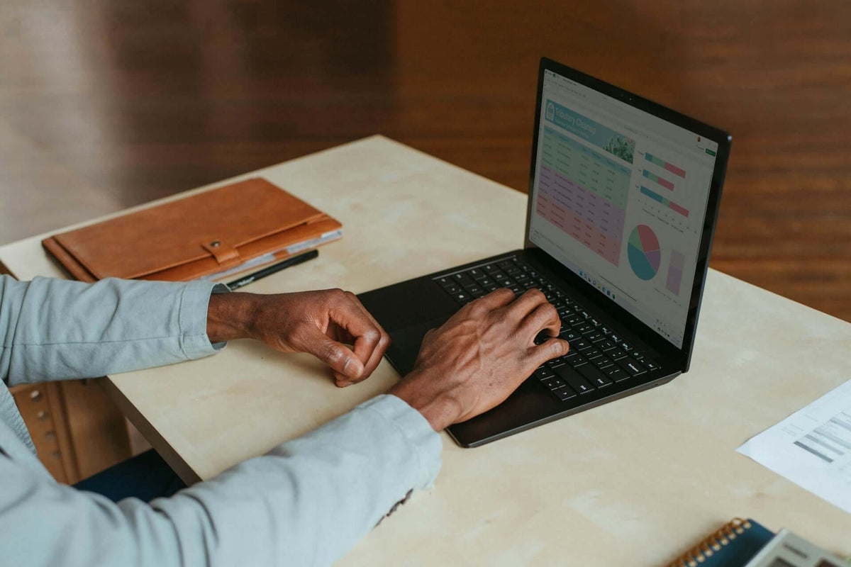 Person working on a laptop with charts and graphs, showcasing home office essentials: your work from home wishlist.