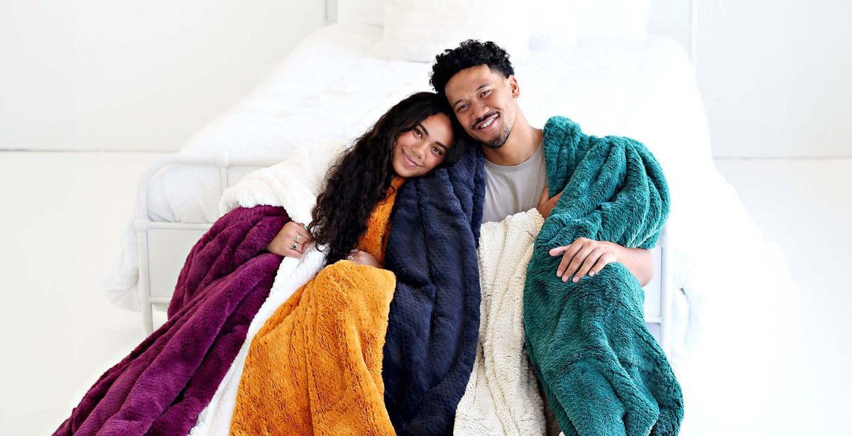 Home is Where the Heart is 13 of the Best Indoor Date Ideas: couple snuggled in colorful blankets on a cozy bed.