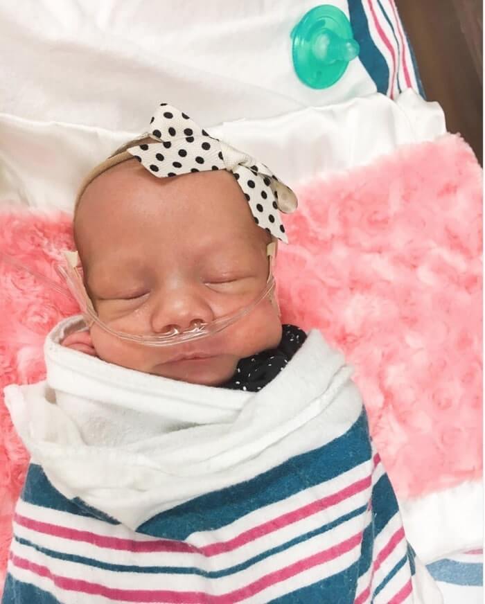 Heart of Minky: Indie wrapped in a blanket, peacefully resting with a polka dot bow in the NICU.