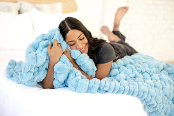 Transform Your Bedroom into a Cozy Space: Ideas & Tips - woman embracing fluffy blue blanket on a bed