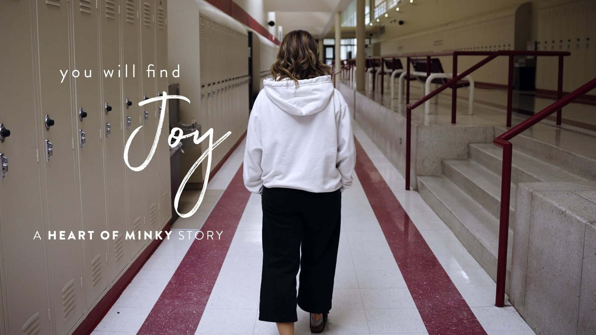 You will find Joy A HEART OF MINKY STORY with a person walking in a school hallway.