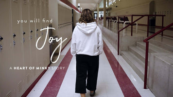 You will find Joy A HEART OF MINKY STORY with a person walking in a school hallway.