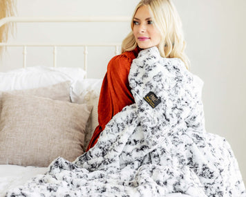 Cozy bedroom scene featuring a woman wrapped in a stylish blanket, perfect for the article '9 Ways to Style Your Bedroom for Winter'.
