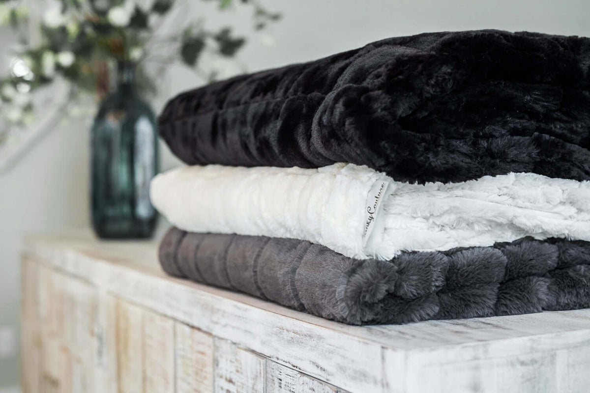 Stack of Minky Couture blankets in various colors showcasing different blanket thicknesses.