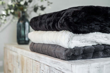 Stack of Minky Couture blankets in various colors showcasing different blanket thicknesses.