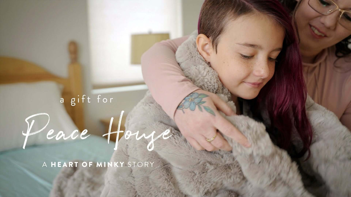 A warm embrace showcasing a girl snuggled in a cozy blanket, representing a gift for Peace House, a Heart of Minky Story.