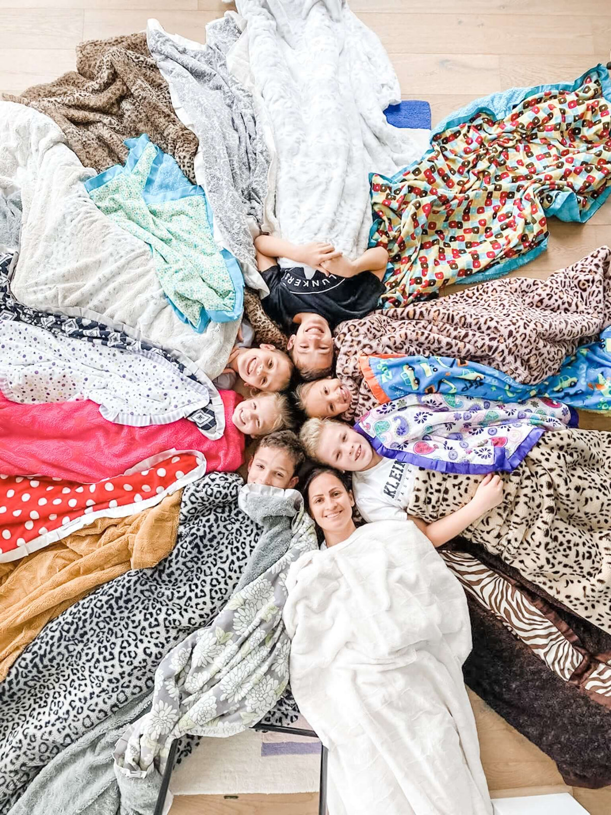 A group of kids lying in a circle with their heads together wrapped in Minky Couture blankets