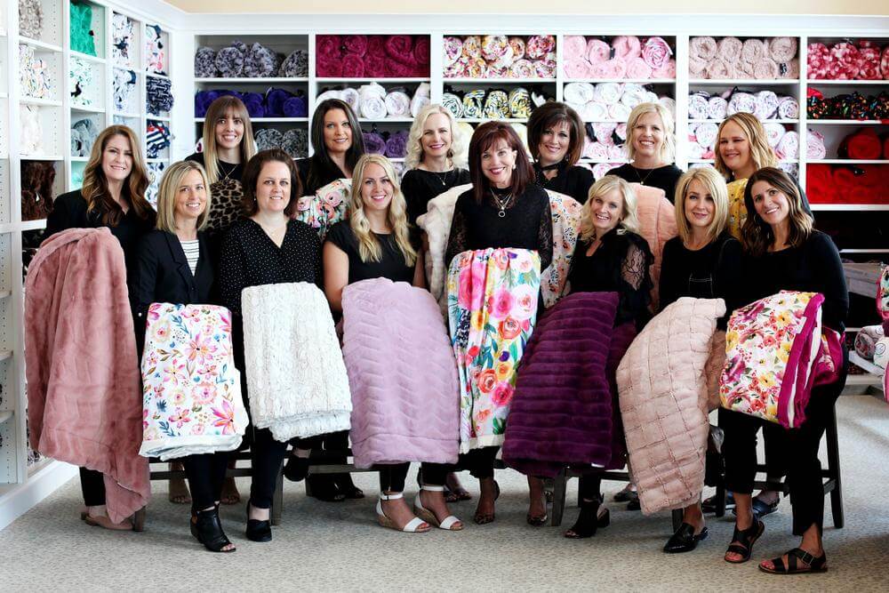 Hi There! *Waves* - Minky Couture team showcasing designer blankets in a cozy atmosphere.