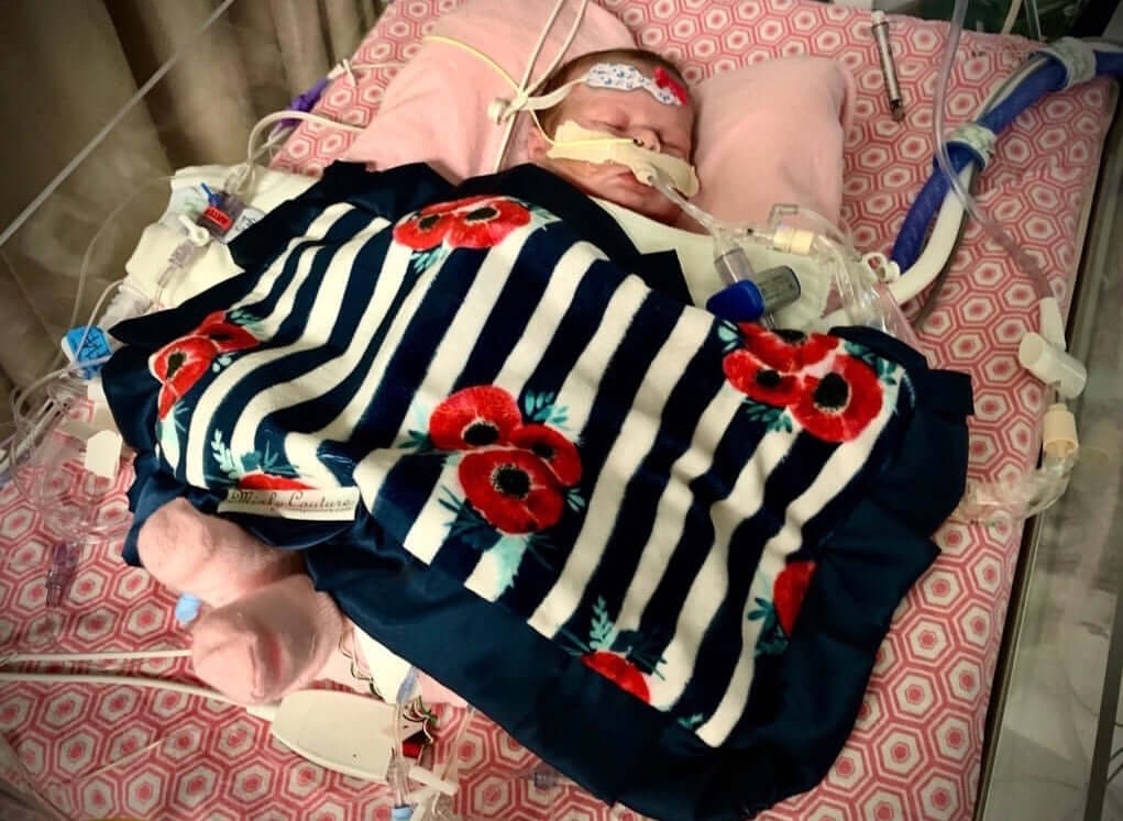Heart of Minky: Miracle Morgan in hospital, wrapped in a colorful blanket, surrounded by medical equipment.