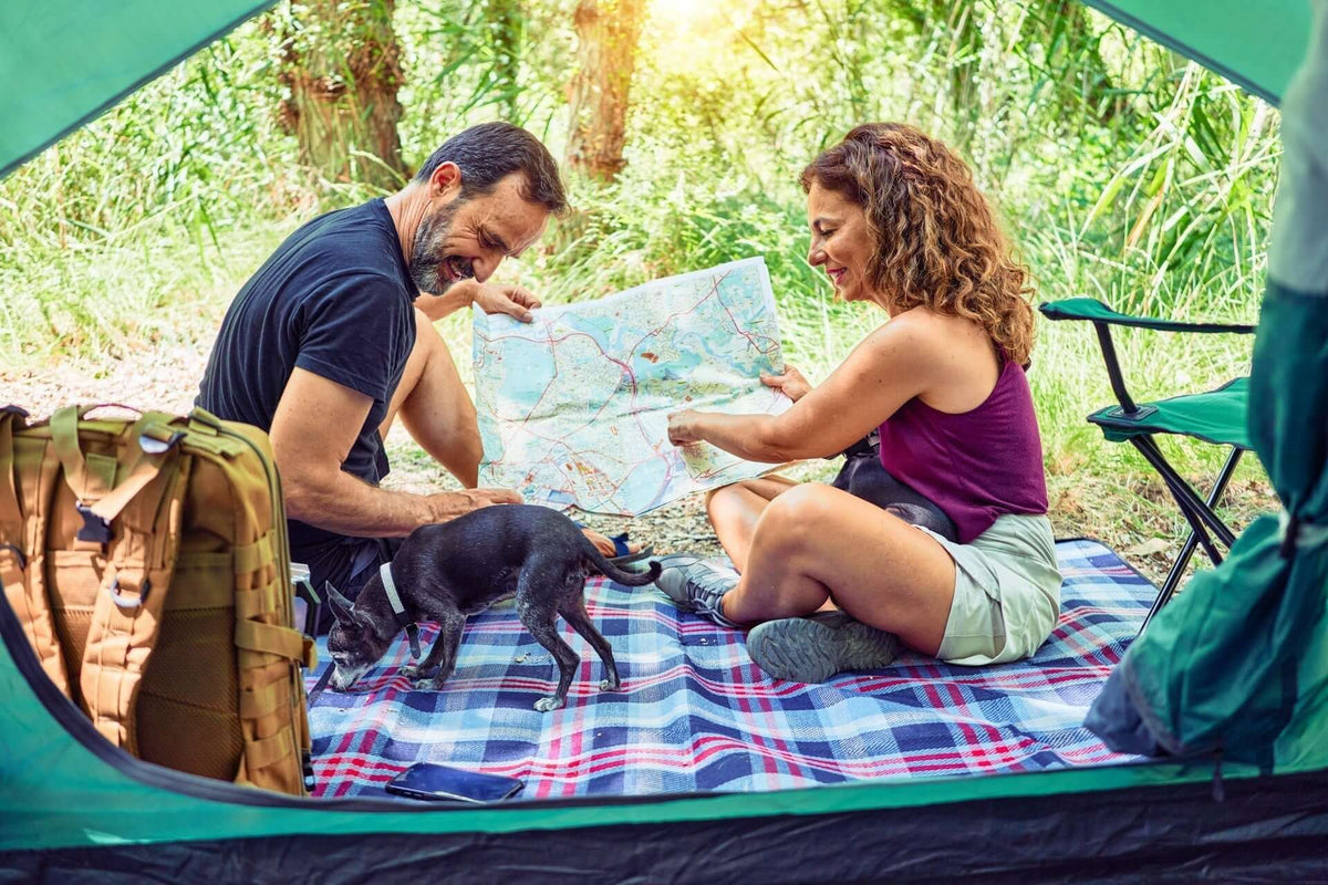 Outdoor Travel Blankets: Camping Essentials for Travelers in use by a couple with a dog inside a tent.