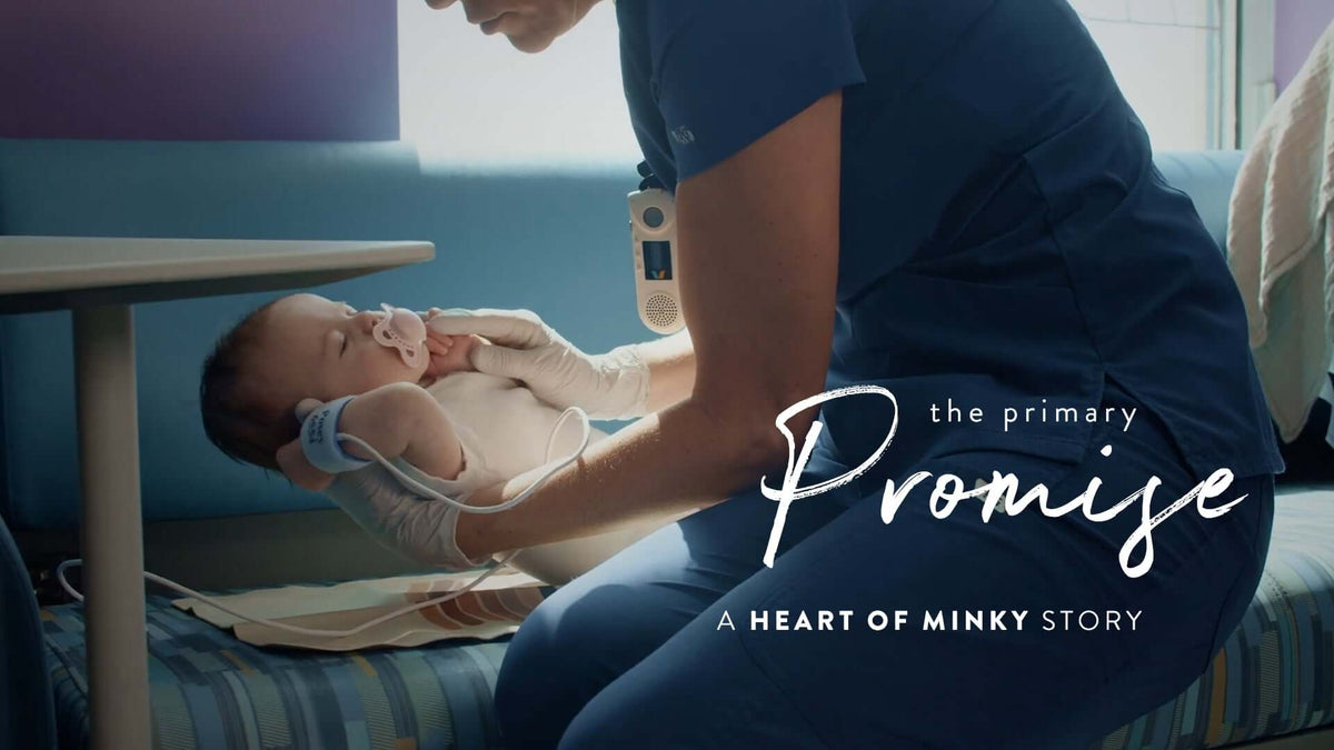A caregiver holding a baby in a hospital setting with the text 'the primary Promise - A Heart of Minky Story' overlay