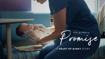 A caregiver holding a baby in a hospital setting with the text 'the primary Promise - A Heart of Minky Story' overlay
