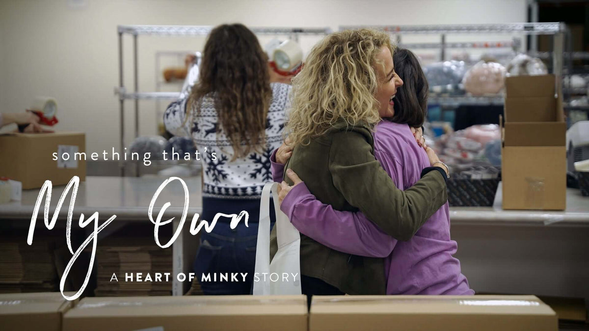 Something that's My Own - A Heart of Minky Story, depicting a warm embrace in a community setting.