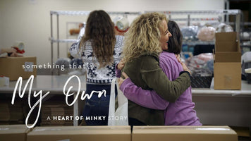 Something that's My Own - A Heart of Minky Story, depicting a warm embrace in a community setting.