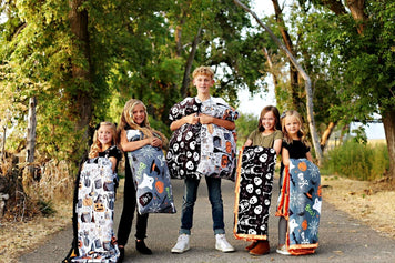Did Someone Say Halloween? Kids showcasing new Halloween blankets in fun spooky patterns outdoors.