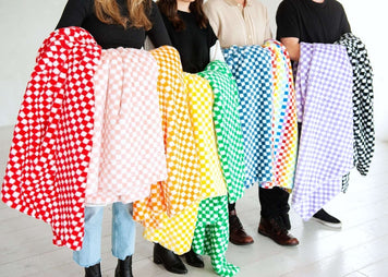Colorful checkered blankets held by four models, showcasing a variety of vibrant patterns and textures.