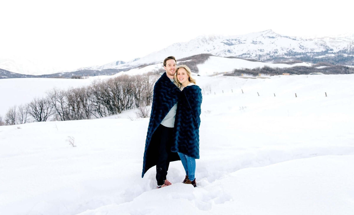 Couple enjoying a snowy landscape in Salt Lake City while wrapped in blankets during winter activities.