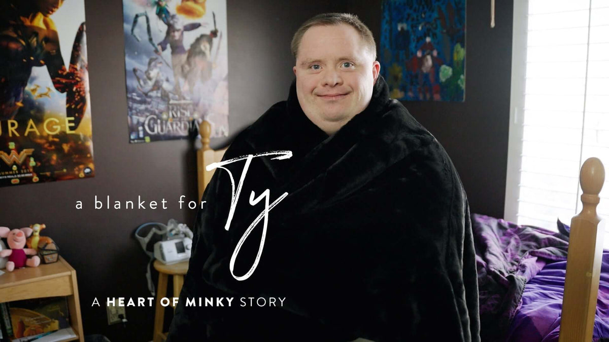 A blanket for Ty A Heart of Minky Story featuring a young man wrapped in a cozy black blanket.