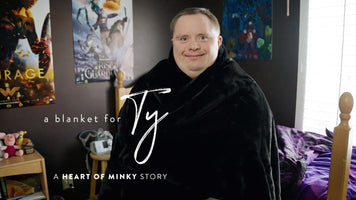 A blanket for Ty A Heart of Minky Story featuring a young man wrapped in a cozy black blanket.