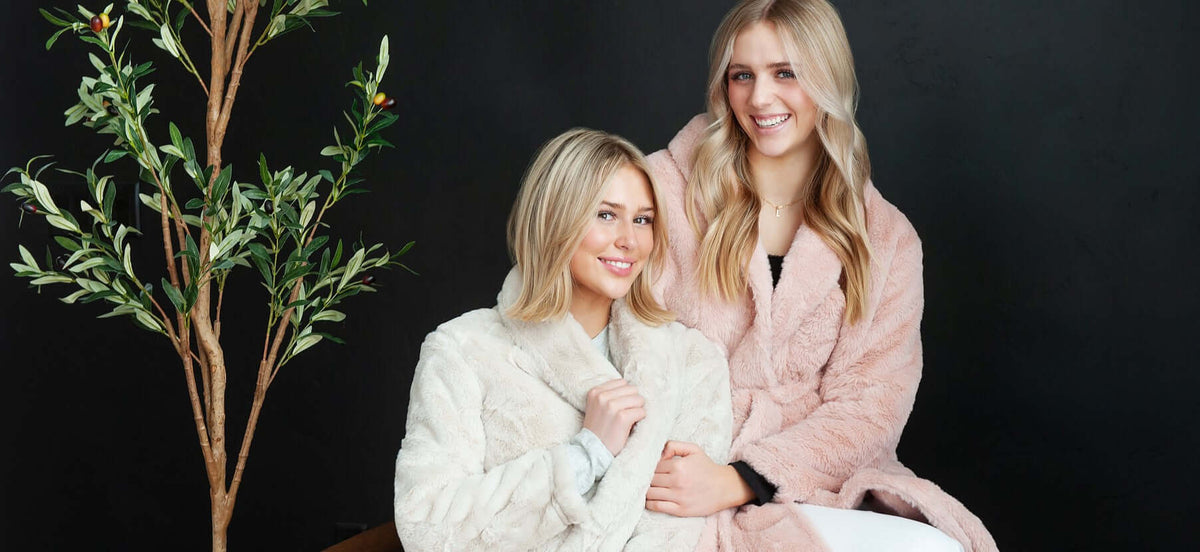 Two women in cozy robes sitting together, promoting self-care with comfort and relaxation in mind.