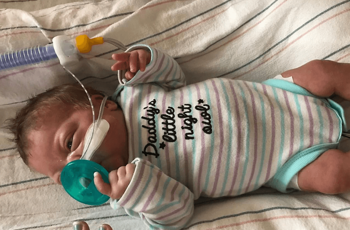 Heart of Minky: Vivian, a baby in a striped onesie with a pacifier in the NICU.