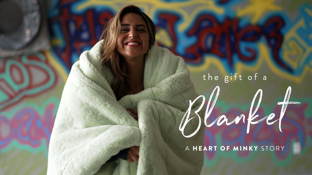 Woman smiling while wrapped in a soft blanket, representing the Heart of Minky Story - The Gift of a Blanket