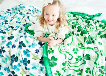 A girl smiling under a colorful shamrock blanket, perfect for celebrating St. Patrick's Day and learning how to catch a Leprechaun!