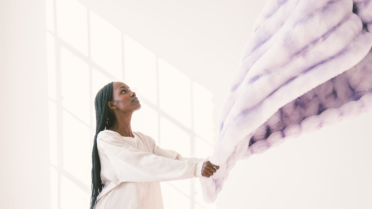 Woman holding a weighted blanket while learning how to wash a weighted blanket at home.