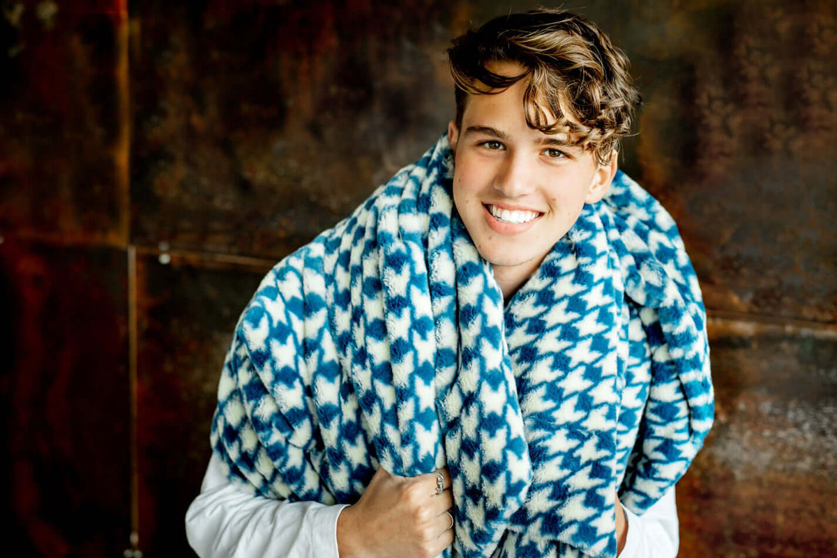QUIZ: Do You Know The Names Of These Minky Blankets? Young man smiling while wrapped in a blue and white Minky blanket.