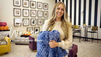 Woman holding a blue Minky blanket in a stylish store, representing the Heart of Minky Story Reflection on Growth.