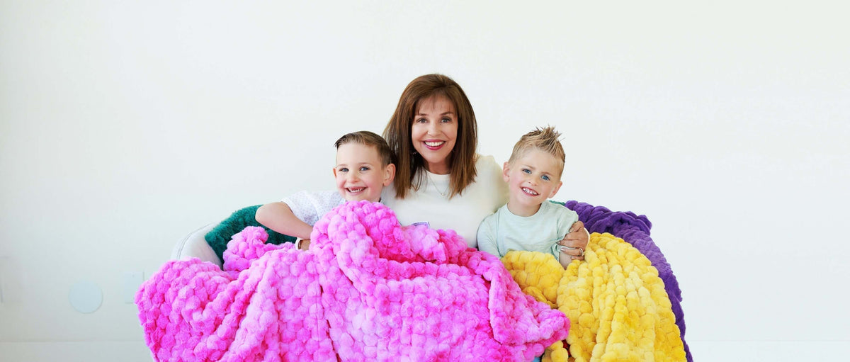 Heart of Minky Story $3 Million Donation to Autism Services with a woman and two children wrapped in colorful blankets.