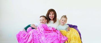 Heart of Minky Story $3 Million Donation to Autism Services with a woman and two children wrapped in colorful blankets.