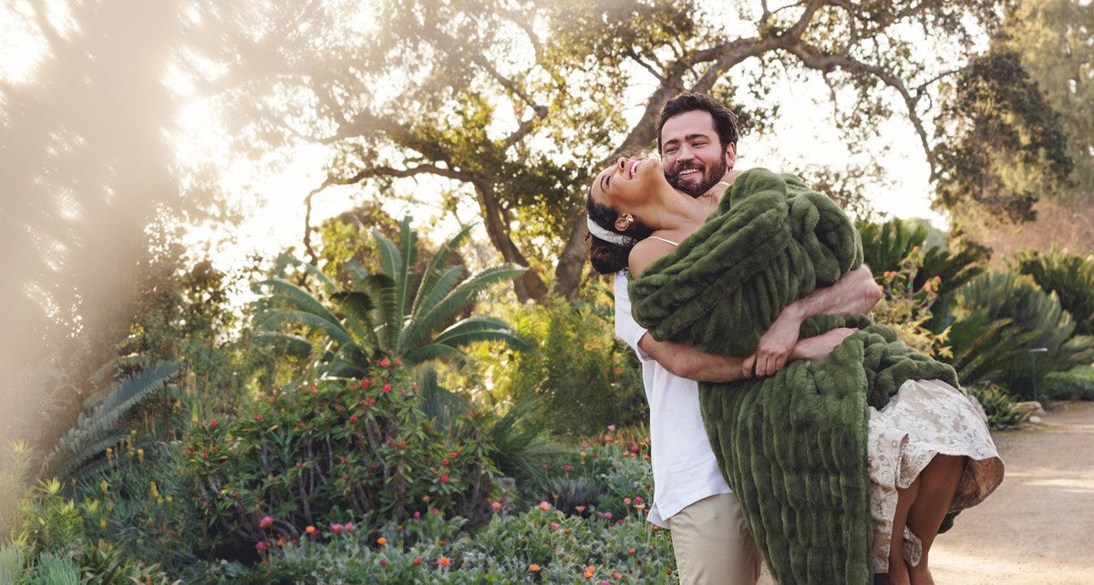 Couple enjoying a romantic moment outdoors, embracing amidst lush greenery, perfect for wedding registry ideas.