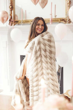 Woman smiling, wrapped in a Hugs Sophia Cream Gingham Minky Couture blanket.