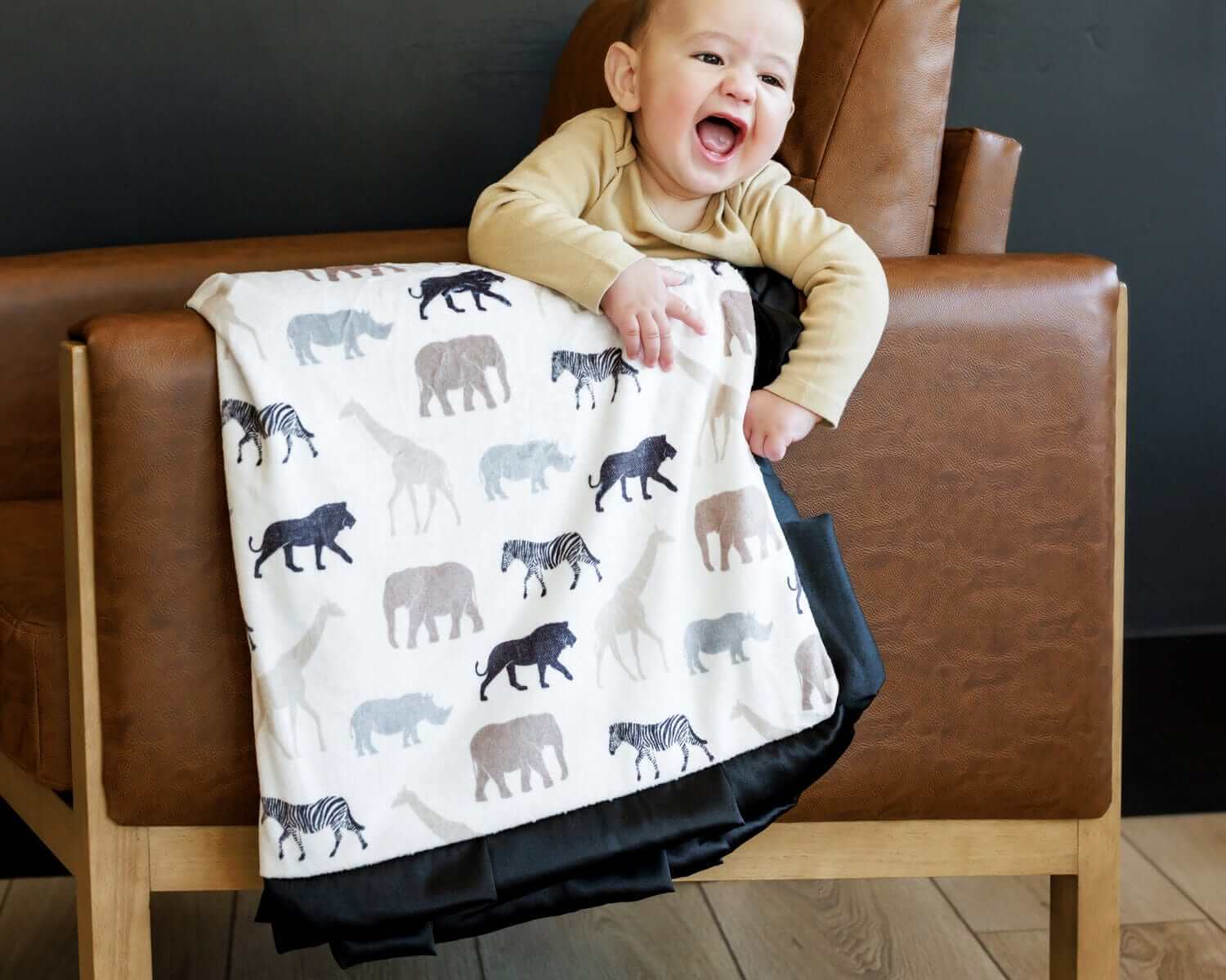 Adorable child laughing with Safari Blanket featuring animal silhouettes, perfect for little explorers.
