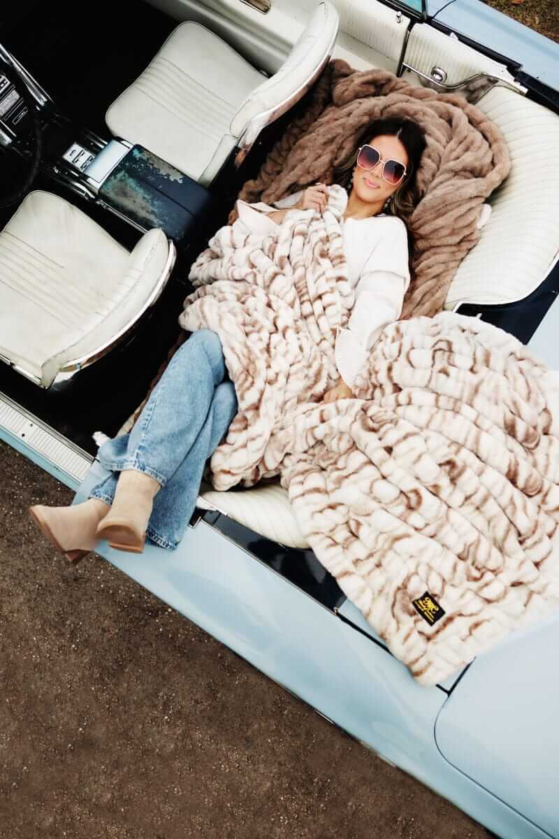 Woman relaxing in a vintage convertible, wrapped in a plush Minky Couture blanket.