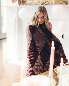 Woman wrapped in a plush Minky Couture blanket, looking down and smiling.