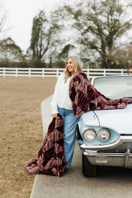 Woman standing by a vintage car, wrapped in a plush Minky Couture blanket.