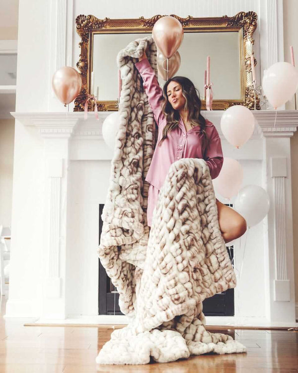 Woman posing with a faux fur Minky Couture Hugs Kaci Chocolate Marble blanket.