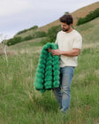 Model holding the Ultra Sorbet Kelly Green weighted blanket in a natural setting, showcasing its vibrant color and plush texture.