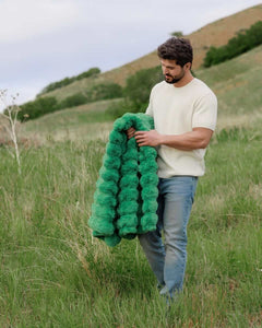 Model holding the Ultra Sorbet Kelly Green weighted blanket in a natural setting, showcasing its vibrant color and plush texture.