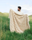 Man holding the Ultra Sorbet Sand weighted blanket outdoors with a soft texture and warm neutral color.
